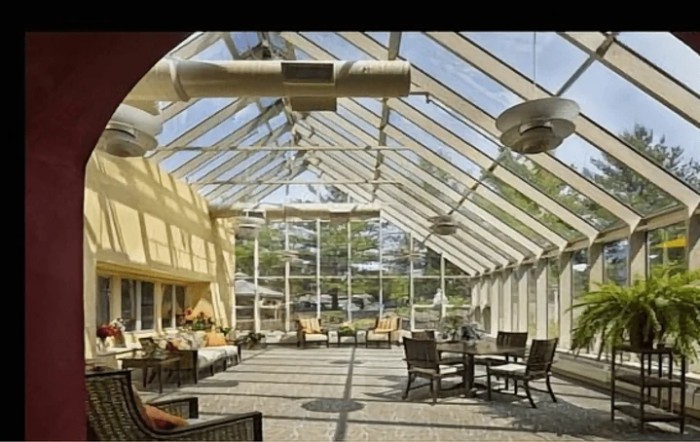 A spacious atrium with a glass ceiling, featuring comfortable seating arrangements and ample natural light.