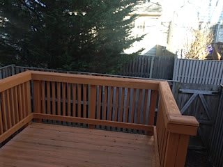A wooden deck with a railing overlooking a backyard.
