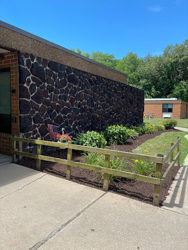 A well-maintained garden alongside a brick building featuring a textured stone wall.
