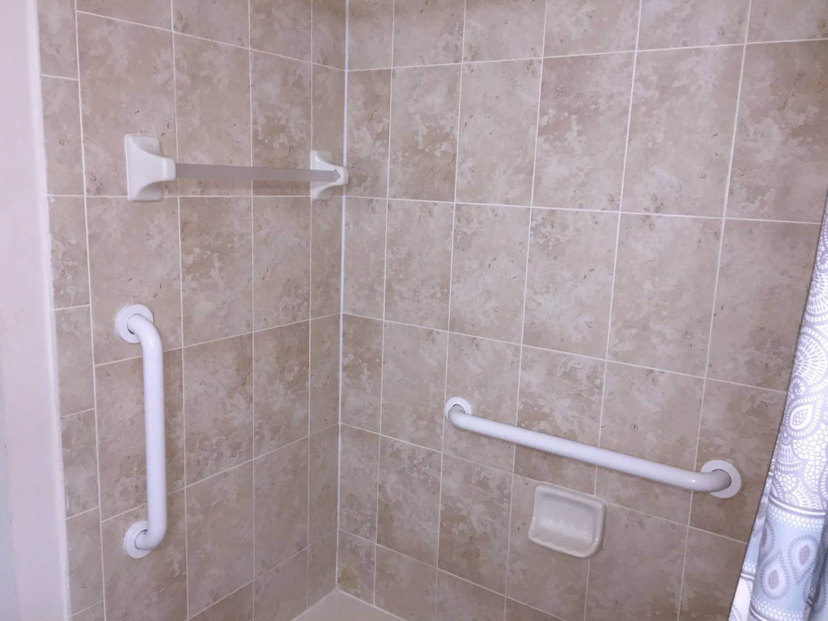 A tiled shower area equipped with safety grab bars.