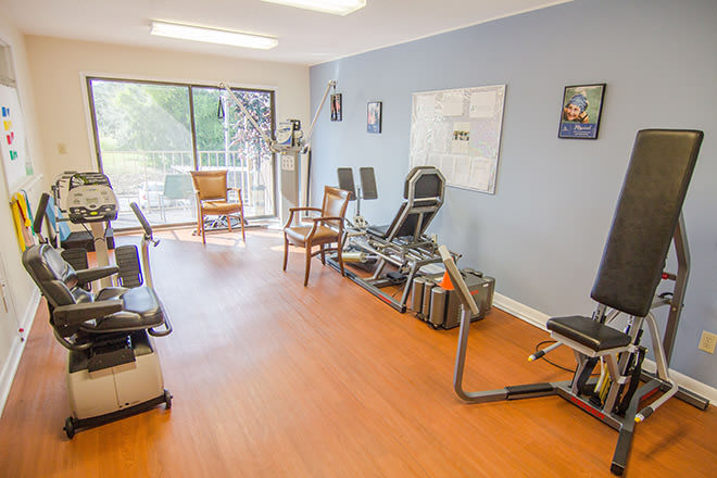 A well-lit physical therapy clinic with exercise equipment and chairs for rehabilitation exercises.