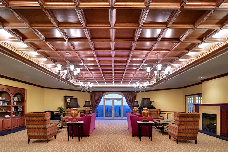 A luxurious hotel lobby with elegant furnishings and a wooden coffered ceiling.