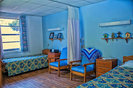 A serene hospital room featuring two beds and cozy seating arrangements.