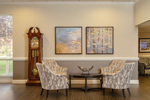A cozy living room corner featuring elegant chairs, wall art, and a classic clock.