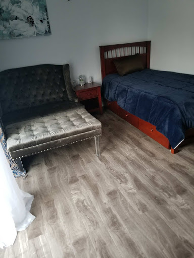 A cozy bedroom featuring a bed and vintage chair on wooden flooring.