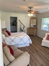 A cozy bedroom with a bed, dresser, and comfy chairs.