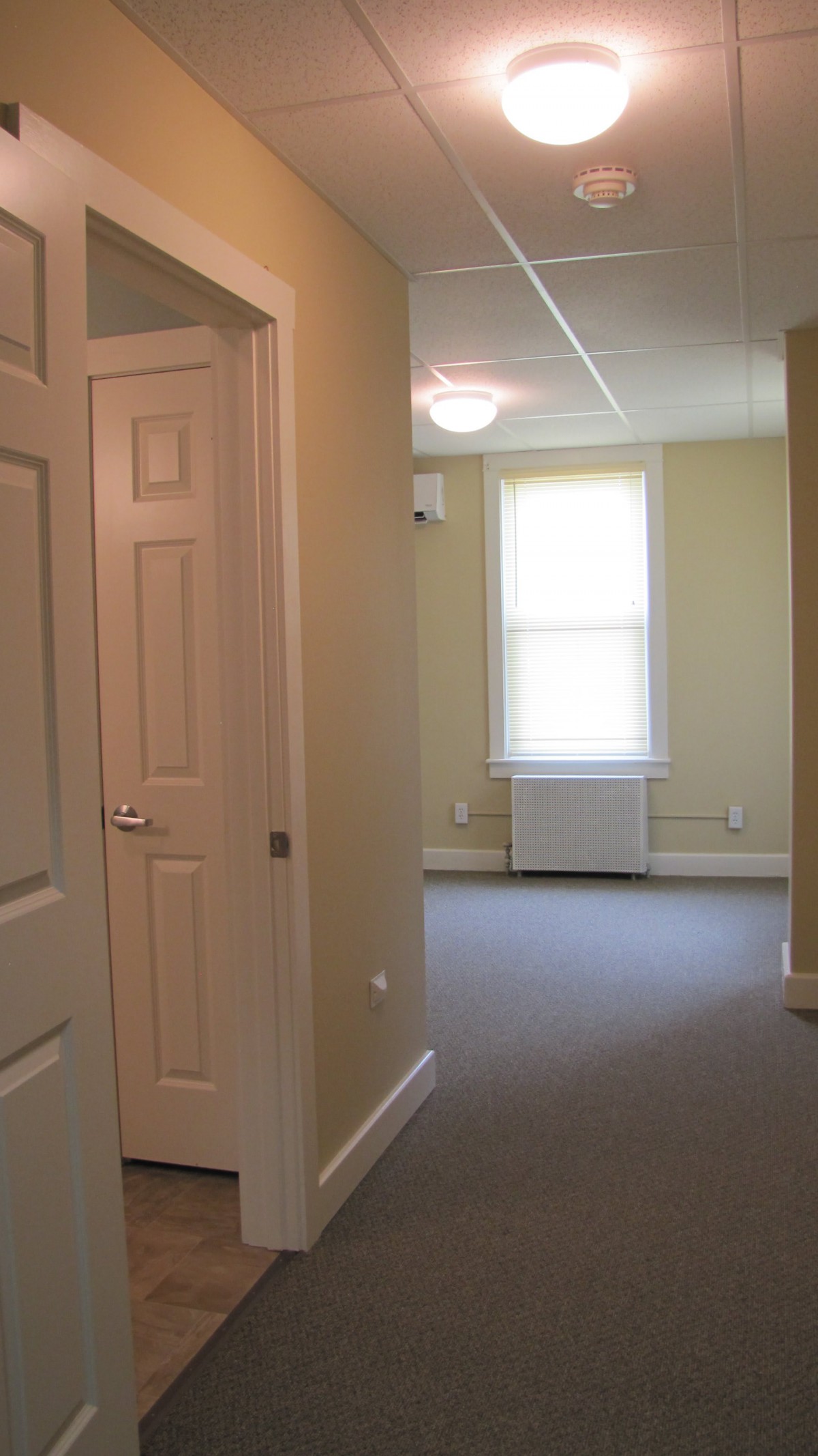A view of an empty room with a window and hallway.