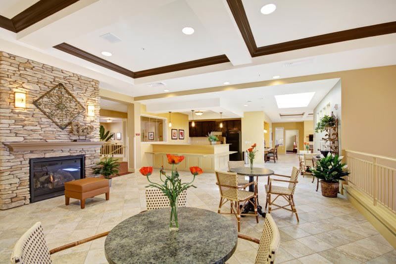A modern hotel lobby with a reception desk, seating area, and decorative plants.