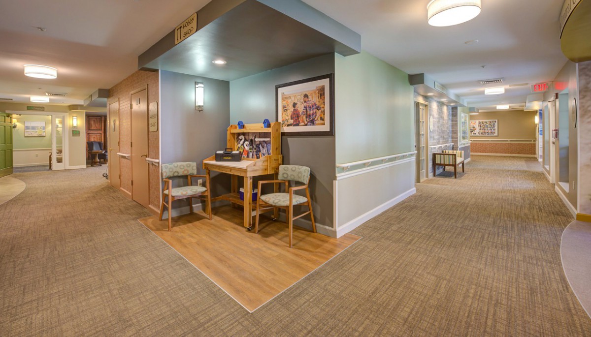 A cozy hallway corner with a wooden desk and two chairs, accented by artwork on the wall.