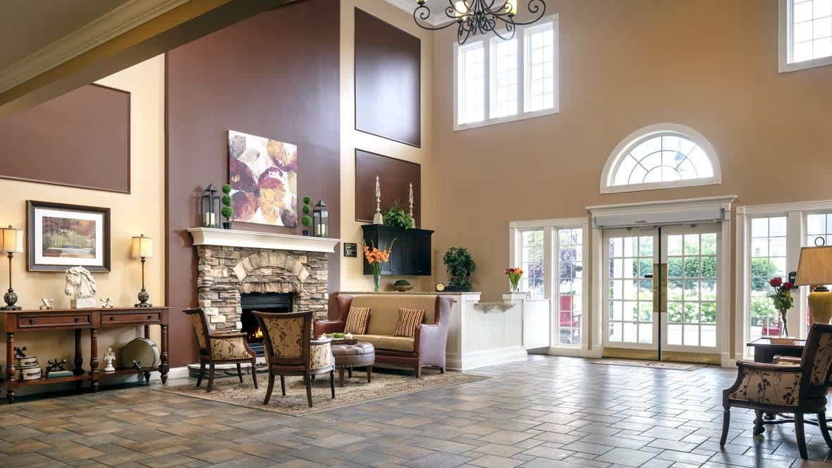 A spacious lobby with a cozy fireplace and seating area, adorned with elegant furniture and a chandelier.