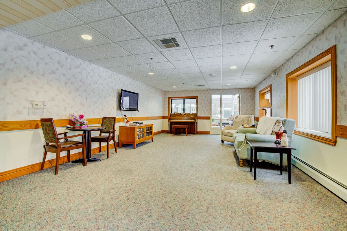 A spacious living room with comfortable seating, a TV, and large windows.
