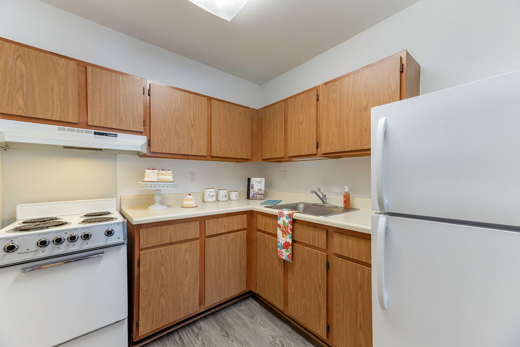 A cozy kitchen with wooden cabinets, a refrigerator, stove, and sink.