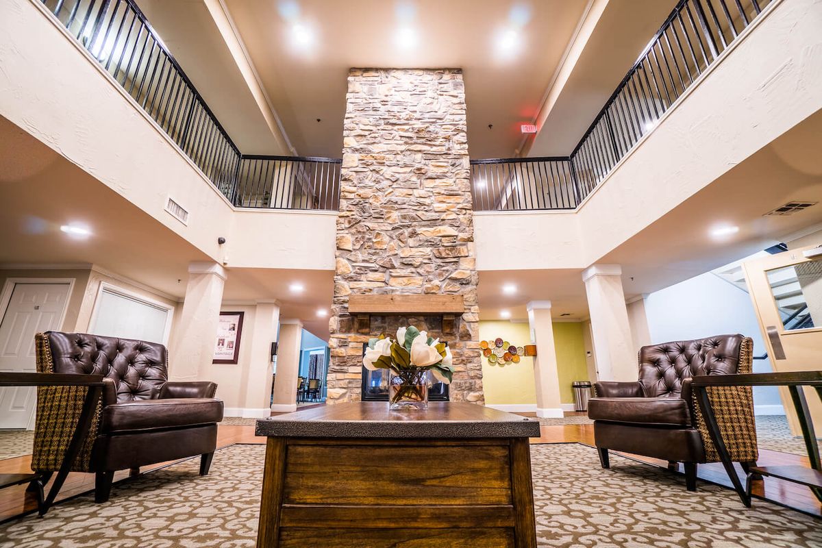 A modern lobby featuring a central stone fireplace and comfortable seating area.