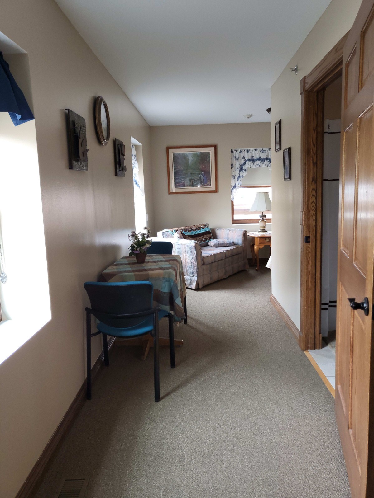 A cozy hallway leading to a living room with furniture and wall decor.
