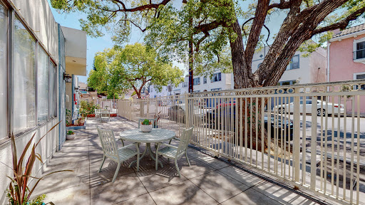 A serene outdoor patio space surrounded by lush trees and a protective fence, perfect for relaxation.
