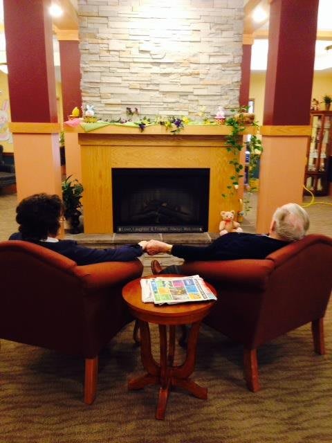 A couple holding hands and relaxing in front of a fireplace.