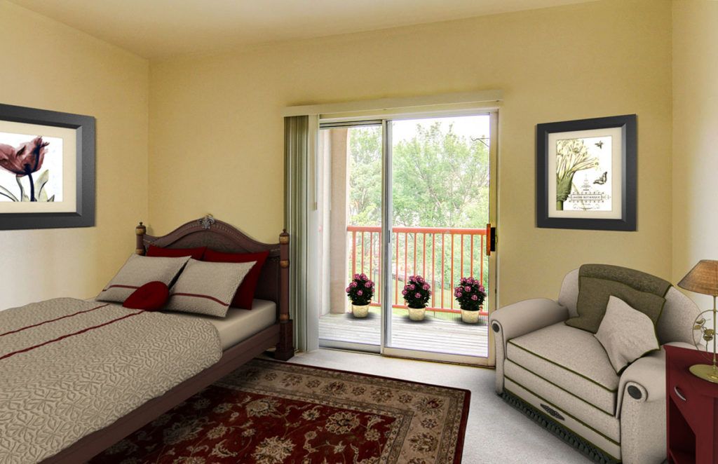 A cozy bedroom with a bed, sofa, and a view of the balcony through sliding glass doors.