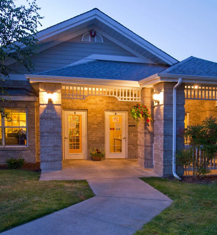 A cozy, well-lit house with a porch in the evening.