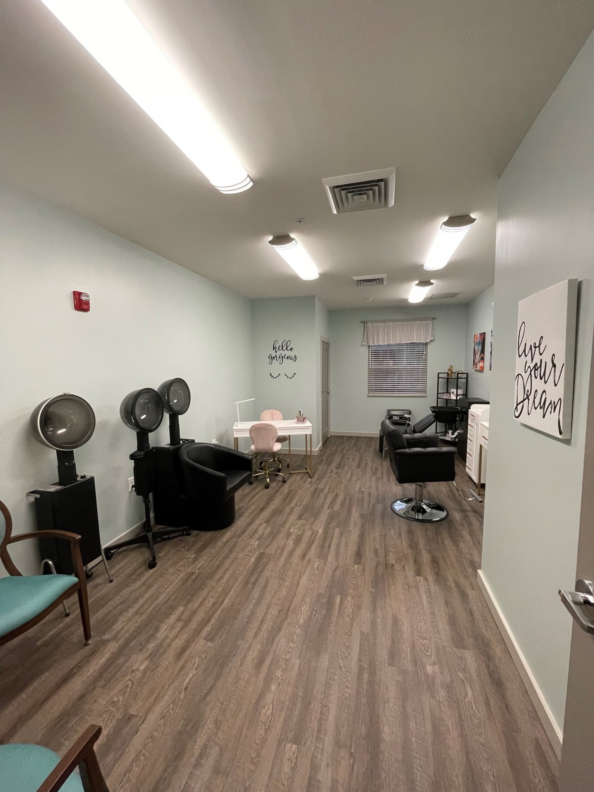 A cozy salon interior with hair dryers, chairs, and soft lighting.