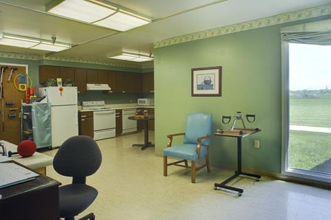 A kitchen area with appliances, chairs, and a small table.