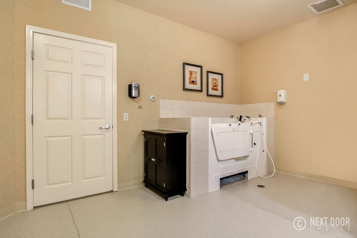 A clean and spacious bathroom featuring a dog wash station with tiled walls.