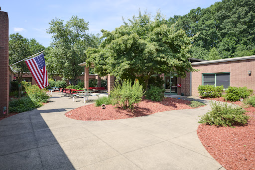 A peaceful outdoor area featuring well-maintained landscaping, a pathway, and an American flag.