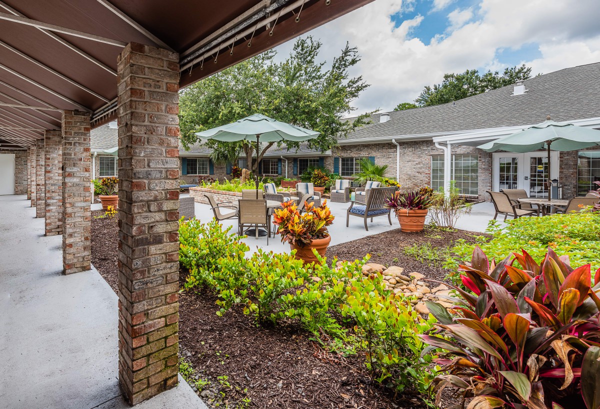 A tranquil courtyard featuring lush gardens and outdoor seating with umbrellas.