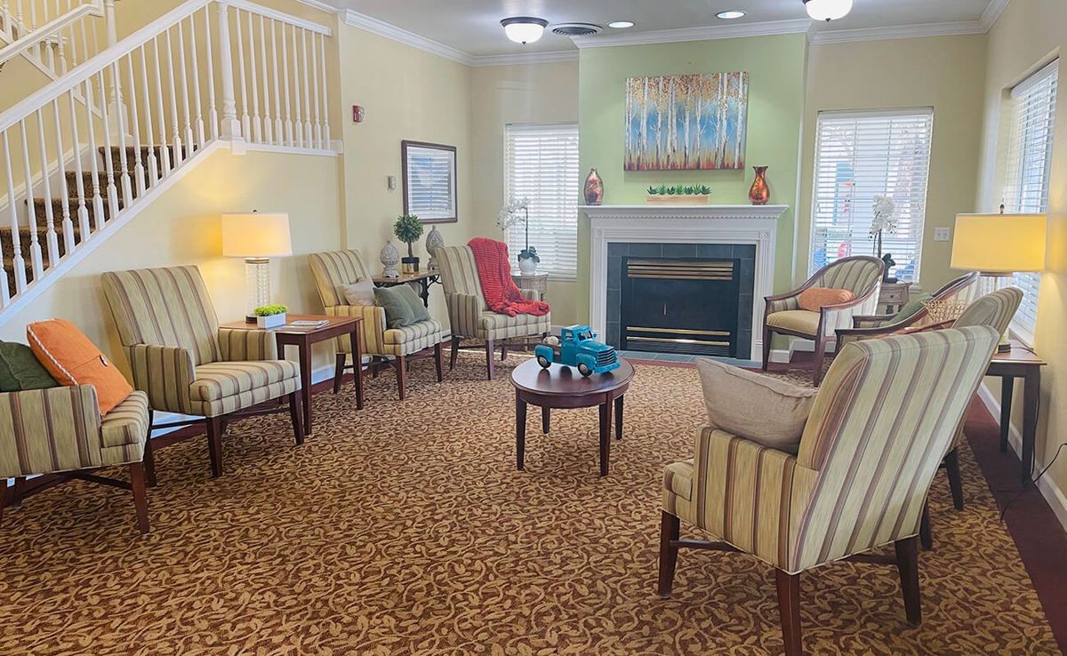 A cozy living room with comfortable seating around a fireplace and decorative artwork on the walls.