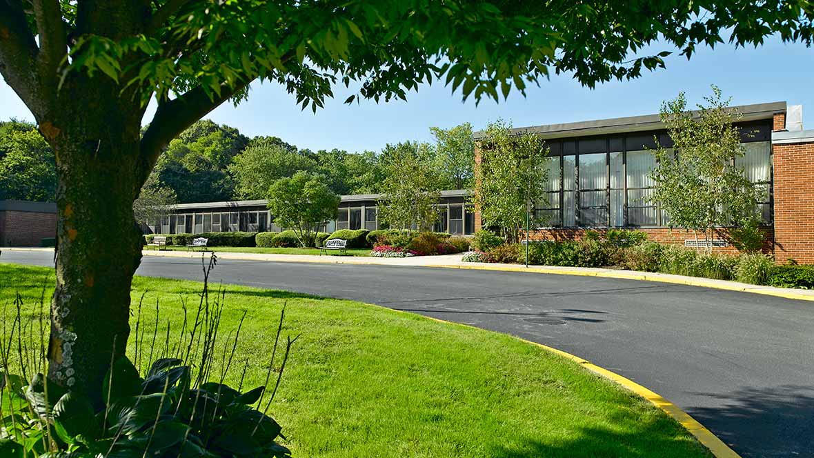 A modern building surrounded by a well-maintained landscape with trees and lush grass.