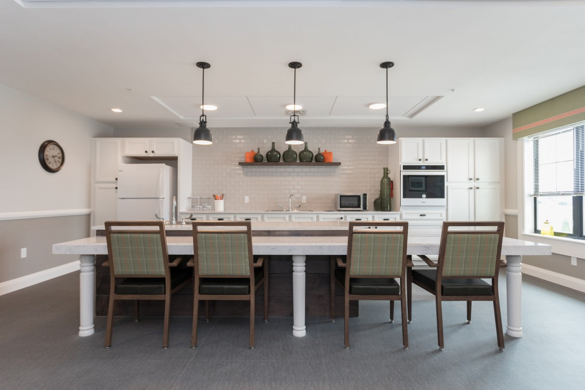A modern kitchen and dining area with a large island, pendant lighting, and sleek decor.