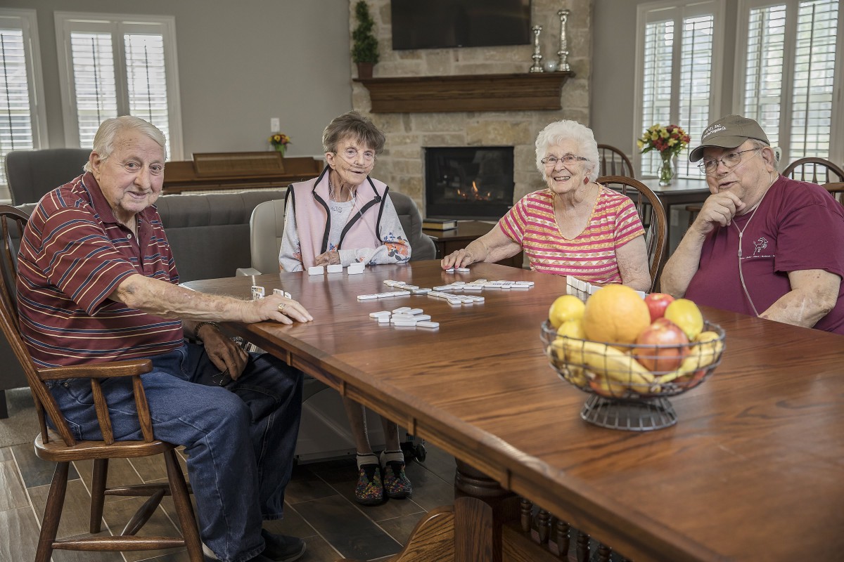 A group of seniors sitting around a table playing cards indoors.