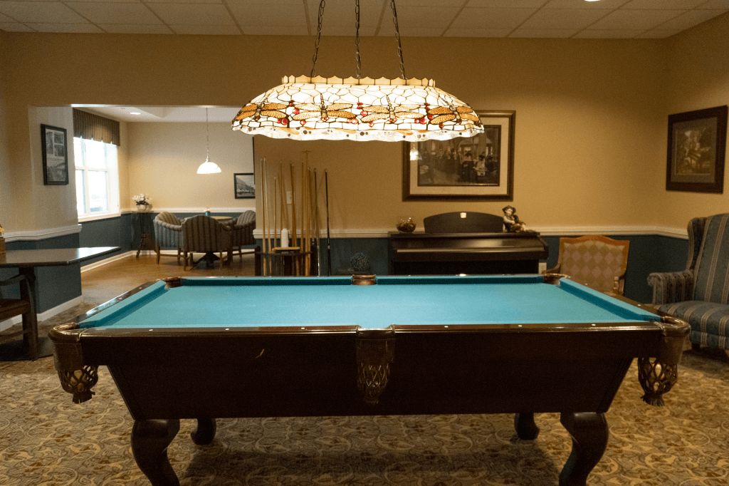 A game room featuring a pool table under decorative lighting.