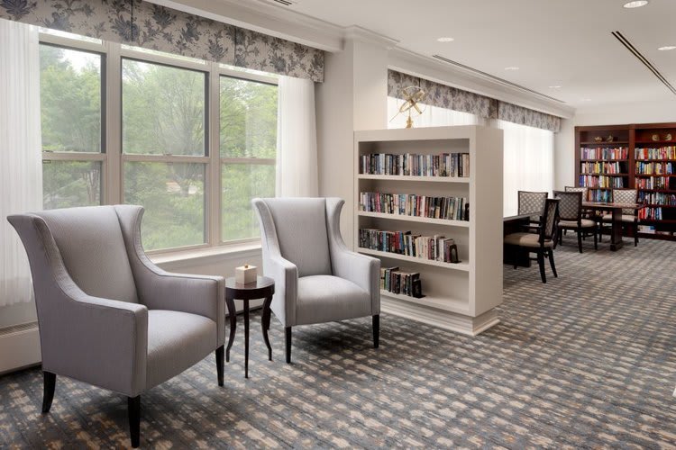 A cozy reading corner with elegant chairs and a bookshelf in a well-lit room.