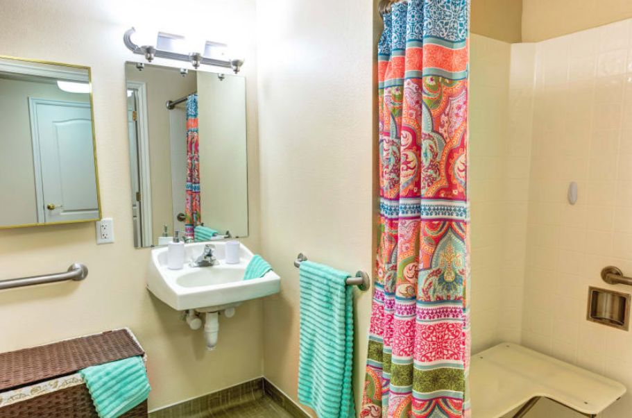 A brightly colored bathroom with a patterned shower curtain and turquoise towel.