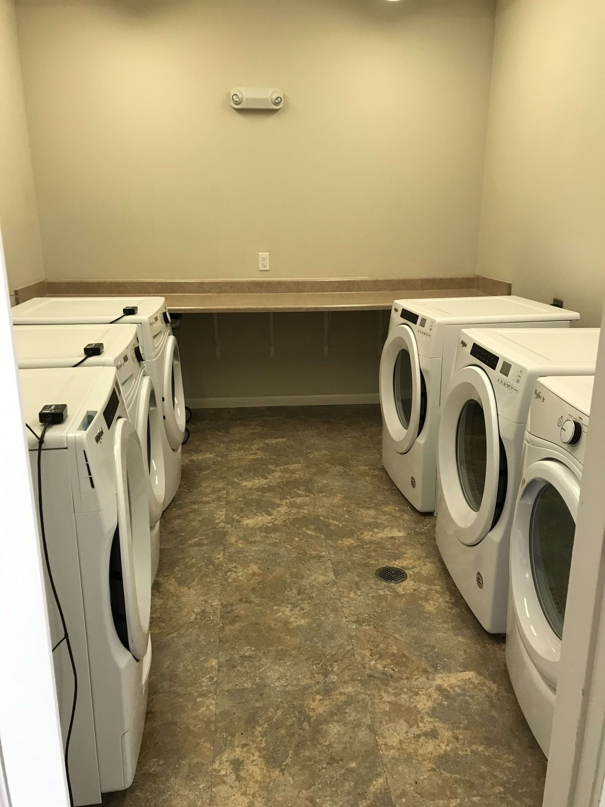 A spacious laundry room with multiple washing machines and dryers lined up against the walls.