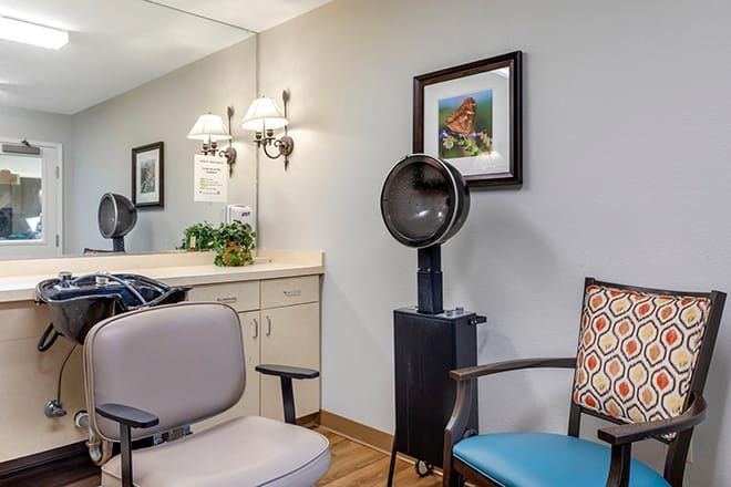 A cozy salon interior featuring a hair dryer, comfortable chairs, and stylish wall art.