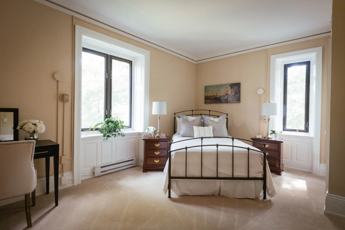 A cozy bedroom with a metal bed frame, flanked by nightstands and lamps, and decorated in neutral tones.