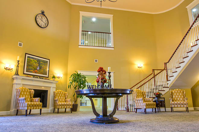 A spacious lobby with elegant decor, featuring a central round table and staircase.