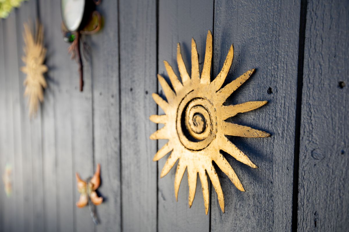 A decorative metal sun with a spiral design mounted on a wooden wall.