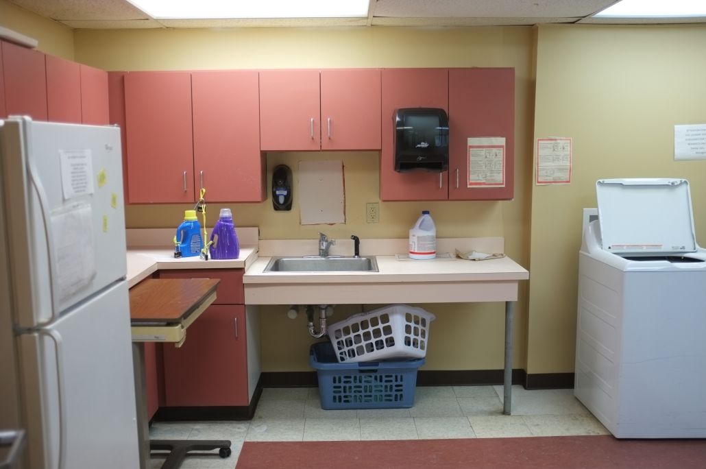 A laundry room with a sink, cabinets, and cleaning supplies.