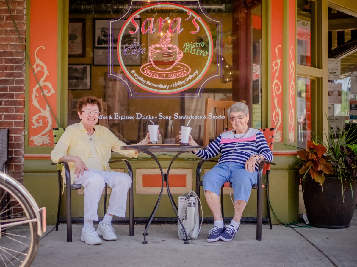 Two elderly friends enjoy coffee together at an outdoor cafe.