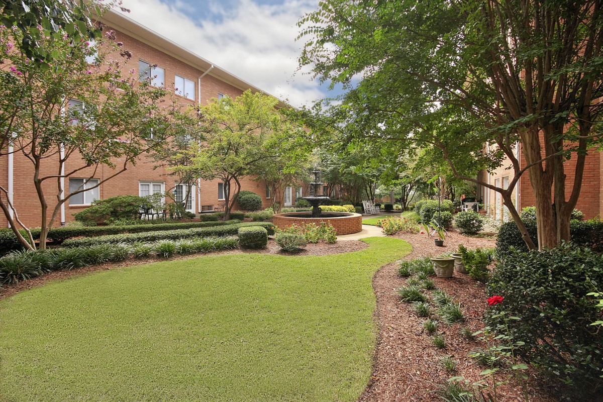 A beautifully landscaped garden with a fountain in an apartment complex courtyard.