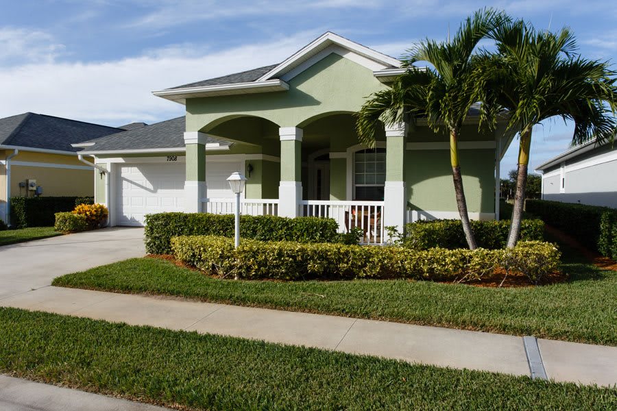 A suburban house with palm trees and well-maintained landscaping.