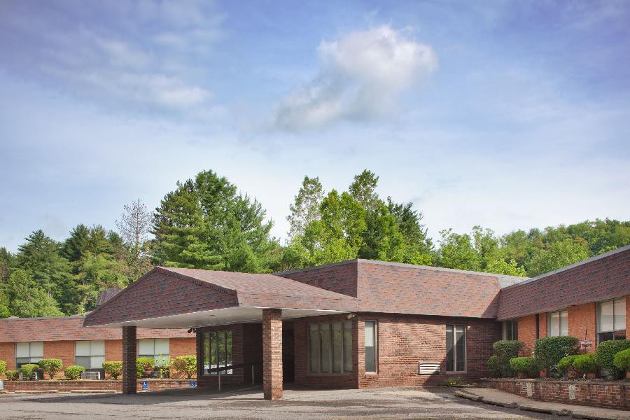 A single-story brick building surrounded by greenery under a blue sky with clouds.