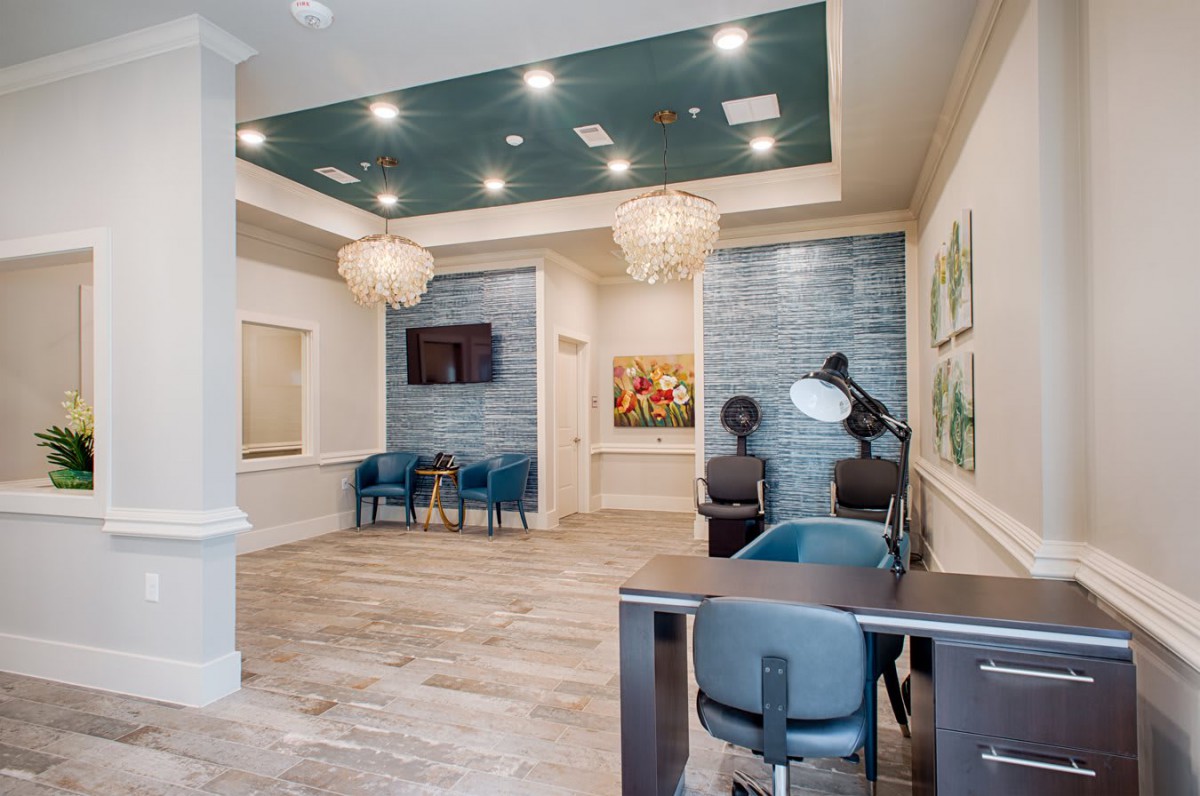 A modern waiting room with comfortable seating, decorative chandeliers, and artwork adorning the walls.