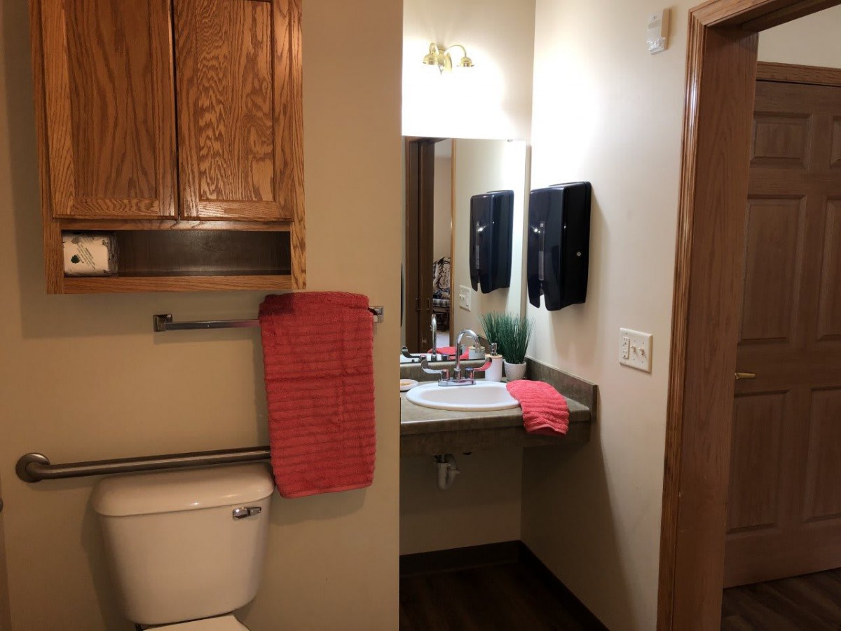 A neatly arranged bathroom with wooden cabinets and red towels.