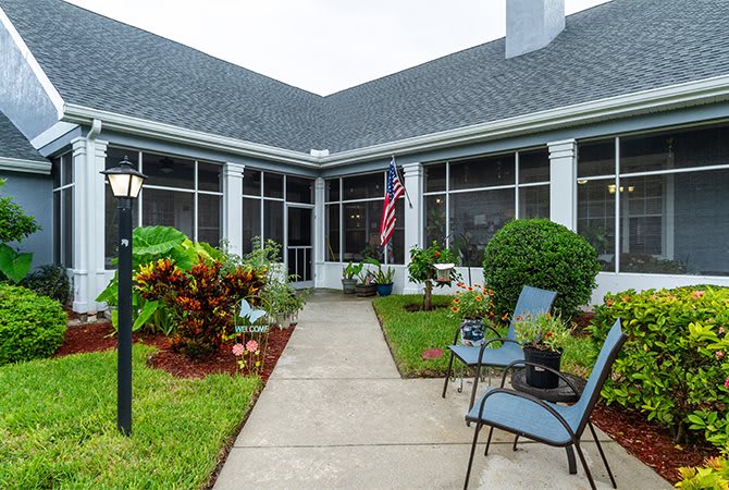 A garden patio with chairs and an American flag in front of a building.