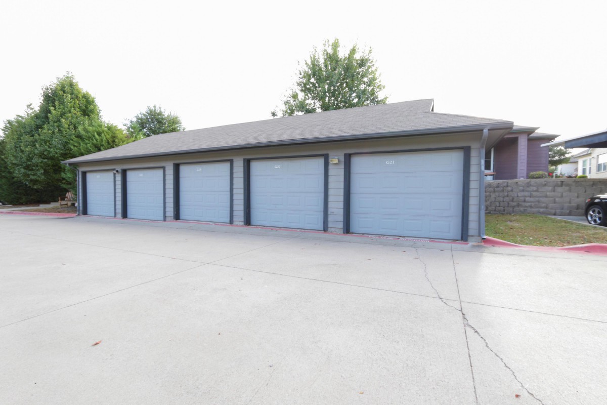 Row of garages with blue doors and a concrete driveway.