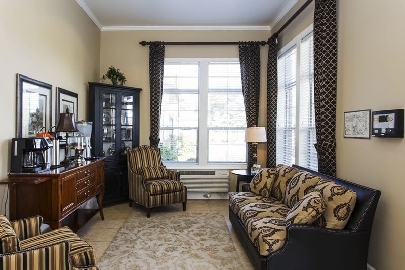 A cozy living room featuring patterned furniture and large windows.