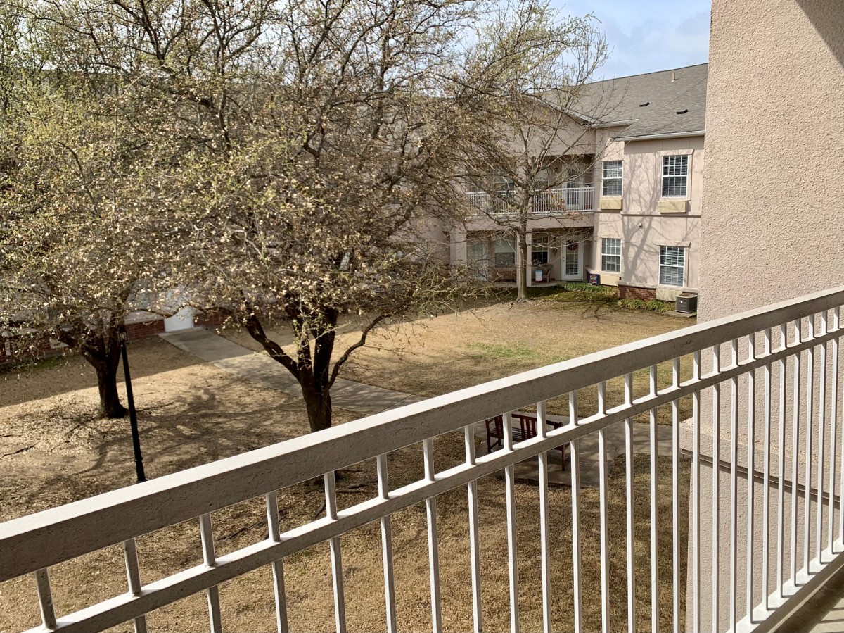 View from a balcony overlooking a courtyard with a tree.